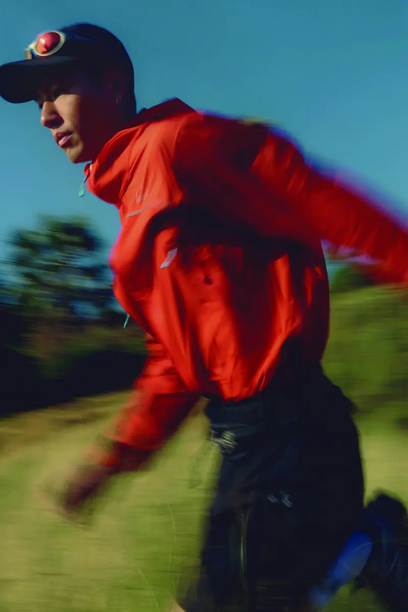 AEON® runner in a red technical jacket mid-stride, motion blurred
