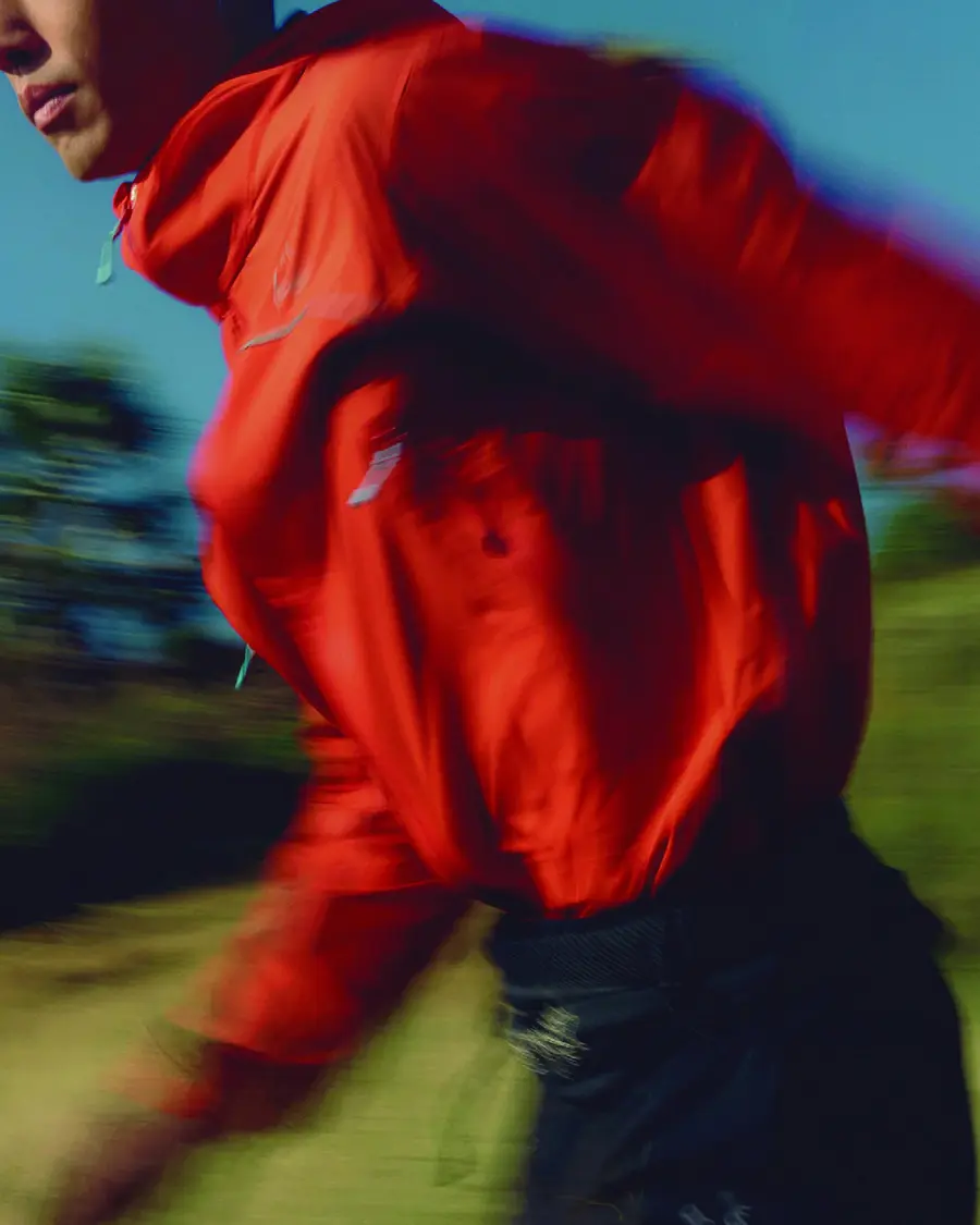 Runner in the signal-red AEON® Storm Shell jacket